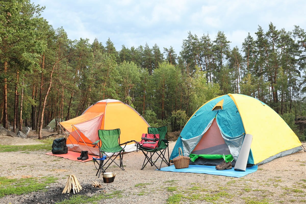 Camping tents and outdoor chairs in a forest campsite representing MAXELTI Active camping gear