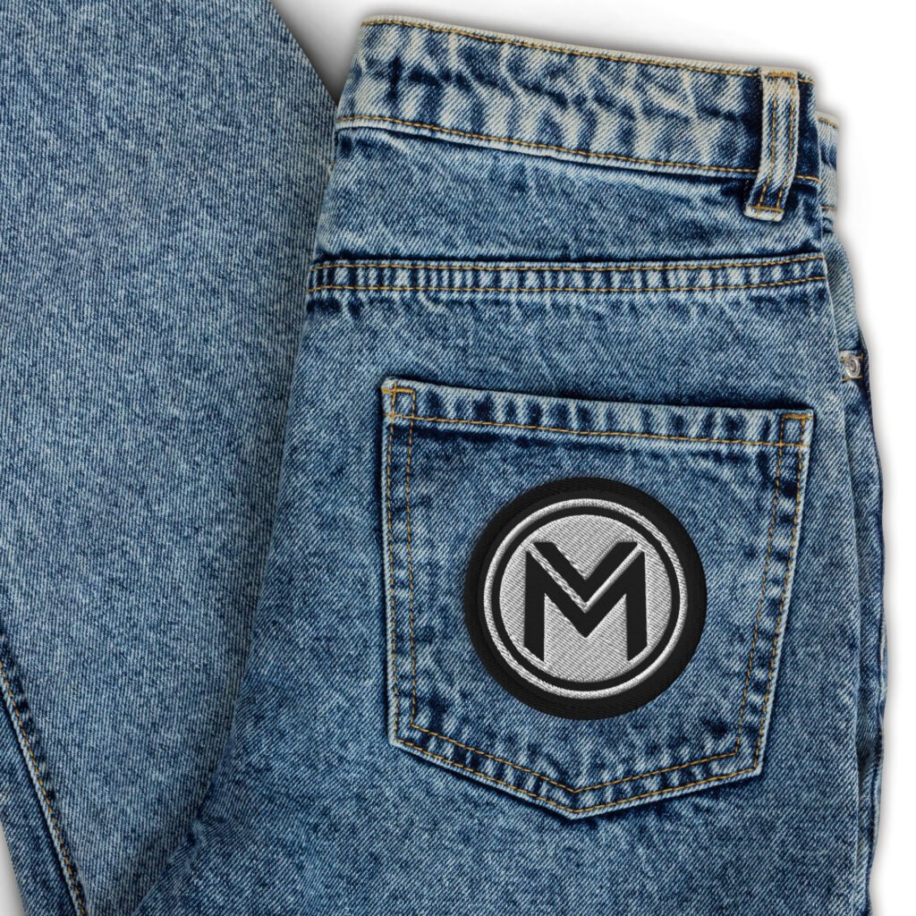 Embroidered patch with the M emblem on a denim back pocket